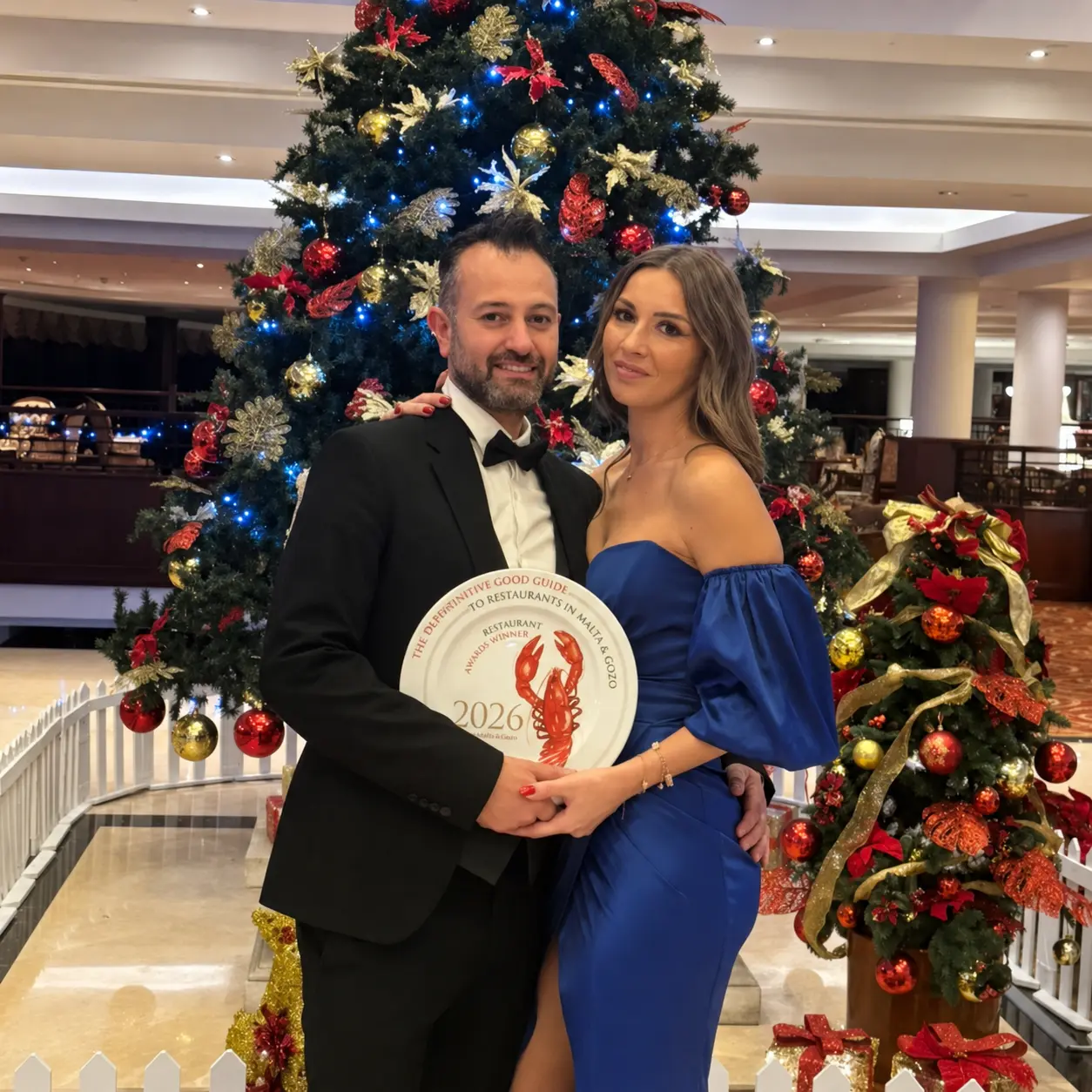 Malcolm and Sherrie holding the 2026 award plate at Christmas